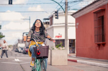 Hispanic Girl Riding A Bicycle.  A Girl Goes To School By Bicycle With Her Books In The Basket.