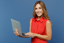 Young Smiling Happy Freelancer Caucasian IT Woman 30s She Wear Red Dress Hold Use Work On Laptop Pc Computer Isolated On Plain Dark Royal Navy Blue Background Studio Portrait People Lifestyle Concept