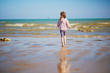 Canvas Print - Preschooler girl playing on the sand beach at Atlantic coast of Normandy, France