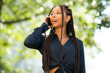 Wall Mural - Beautiful young black woman talking on smartphone outside