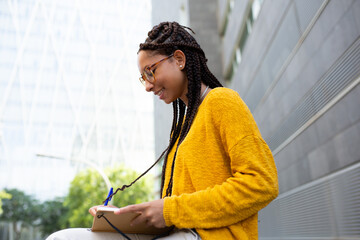 Wall Mural - Woman student sitting outside writing in her book