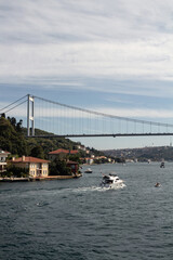 View of yachts on Bosphorus by Kanlica neighborhood on Asian side of Istanbul. FSM bridge is in the background. It is a sunny summer day. Beautiful travel scene.