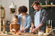 © Mediaphotos - Happy parents teaching their son to prepare salad for dinner while standing at table in kitchen