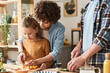 © Mediaphotos - Young mother teaching her son to cut tomato to prepare salad at table in kitchen