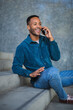 © mimagephotos - Happy man talking on mobile phone while sitting on steps