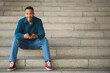© mimagephotos - Man sitting with mobile phone on outdoor steps