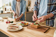 © Mediaphotos - Close-up of young couple preparing sandwiches with vegetables together at table in kitchen