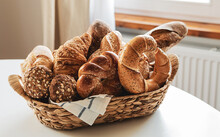 Breakfast - Rustic Basket With Various Kinds Of Bread Rolls On The Table At Home