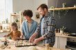© Mediaphotos - Parents with child preparing homemade buns together, they putting them on tray for baking