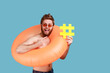 Portrait of happy bearded man standing with orange rubber ring and pointing at yellow hashtag symbol, hash sign of viral web idea, blogging. Indoor studio shot isolated on blue background.