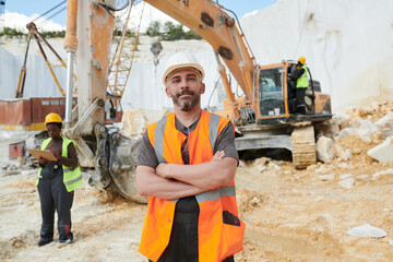 Aufkleber - Confident foreman in reflective vest and safety helmet looking at camera while standing on construction site against caterpillar truck