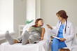 © Studio Romantic - Friendly doctor in blue scrubs and white coat talking to her happy child patient. Teenage school girl lying on examination couch at clinic, looking at her pediatrician and smiling