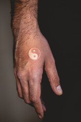 Detail of a yin yang tattoo with white ink in the hand of a guy