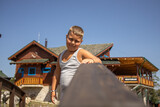 Fototapeta Londyn - a boy with blond hair poses on a wooden bridge and smiles