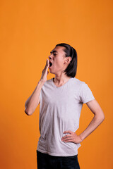 Young adult sleepy asian man yawning, covering mouth with hand. Sleepiness, tired teenager standing, bored lazy person, drowsy teen studio medium shot on orange background