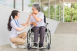 車椅子に乗る高齢者と介護士（肩こり）
