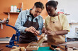© Seventyfour - Waist up portrait of two female artisans in leatherworking shop creating handmade pieces together