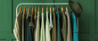 Rack with clothes and hat near green wall in room