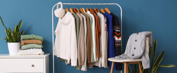 Wall Mural - Rack with stylish sweaters near blue wall in room