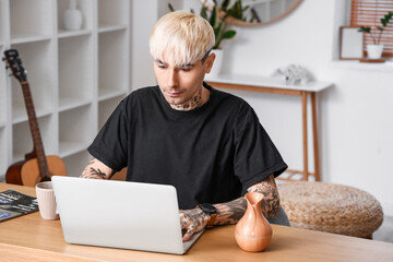 Sticker - Young tattooed man using laptop at home