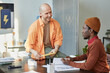 © Seventyfour - Portrait of two men chatting in office wearing bright color clothes while working in creative company