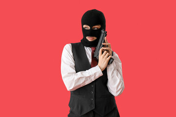 Wall Mural - Young woman in balaclava with gun against red background