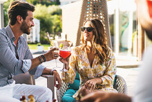 A Young Millennial Generation Couple Celebrates A Toast Sitting In The Resort Garden Clinking Glasses With Imaginative Cocktails - Backyard Recreation - People And Lifestyle Concept