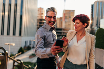 Wall Mural - Urban businessman and businesswoman with smartphone outdoors