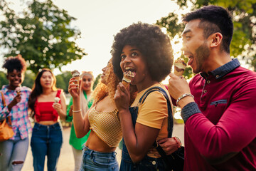 Cheerful friends eating ice cream in city