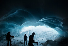 Silhouetted Men Hiking In Glacier Ice Cave, Selkirk Mountains, Canada
