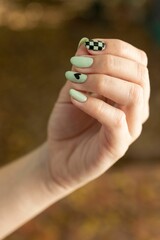 Vertical closeup of a hand of a woman with her pretty manicure design on a blurred background