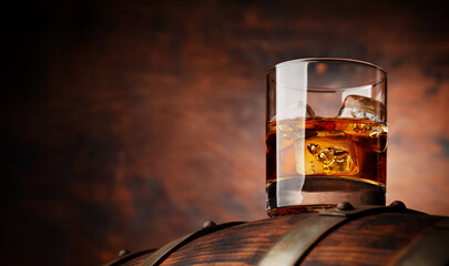 Wall Mural - Glass of whiskey with ice cubes on the old barrel