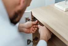 Man Repairing A Cabinet Door Hinge