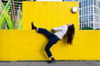 © VISTA by Westend61 - Young woman leaning backwards standing on one leg by wall