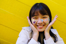 Happy Young Woman With Stickers On Face In Front Of Yellow Wall