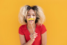 Happy Woman With Mustache Prop In Front Of Yellow Wall