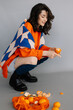 © Максим Галінский - young girl sitting on the floor in a photo studio with tangerines in her hands, posing for a photo, throwing tangerines into the camera, laughing and having fun. Bright emotions