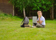 © Ирина Старикова - A smiling Caucasian boy with a briefcase sits on the lawn and reads a book, the concept of education.