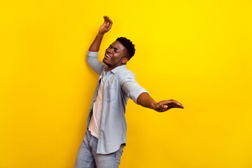 Poster - Photo of optimistic young brunet guy dance wear jeans shirt isolated on yellow color background