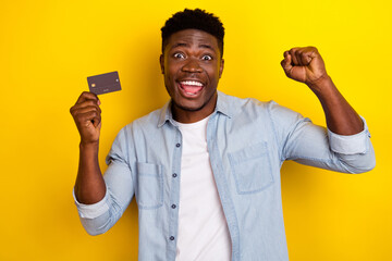 Wall Mural - Photo of ecstatic guy hold credit card fist up celebrate income earnings isolated bright color background