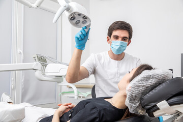 Wall Mural - Dentist adjusting dental lamp in dental office. Dentist turning on lamp before treatment