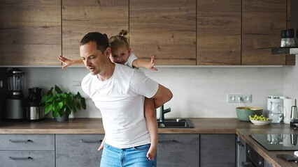 Wall Mural - A happy father and little girl joyfully spending time in a modern kitchen. Happy family. Father's day.