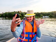 Woman taking picture of herself on smartphone during floating on kayak. Concept of rest, leisure and weekend. Middle Age Woman wearing life vests. Sunny autumn daytime.selective focus