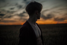 Sexy Man In A Cardigan On A Naked Body With A Rounded Torso At Sunset In A Field.