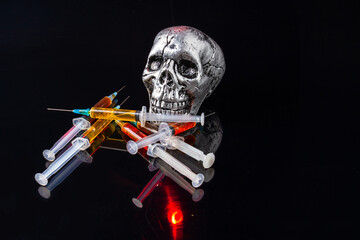 Close-up iron skull with syringes isolated on black background. Pile of syringes filled with heroin or other drug.