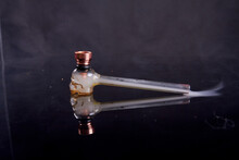 Glass Pipe For Crack Or Crystal Meth On Reflective Mirror Surface. Smoke On Black Background.