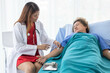 © AllieGraphix - An Asian female doctor is making an injection in the shoulder of a patient in a hospital.
