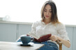 © racool_studio - Bookworm Beauty: Smiling Girl Poses with a Book While Seated on a Chair