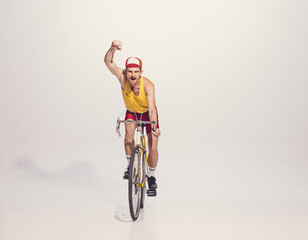 Wall Mural - Portrait of young man in colorful clothes, uniform riding bike isolated over grey background. Sportsman. Winning racer