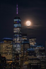 Wall Mural - Vertical of the Manhattan city skyline at nighttime with a full moon.